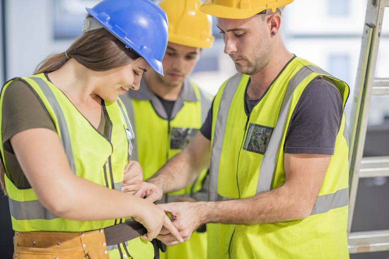 Junge Auszubildende mit Helm und Warnweste